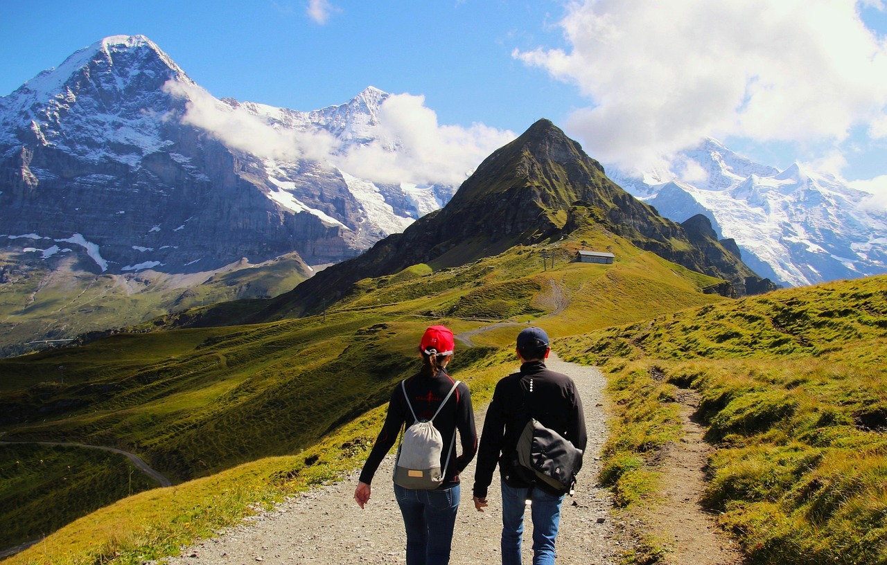 Deux personnes marchant sur une montagne couverte de verdure.