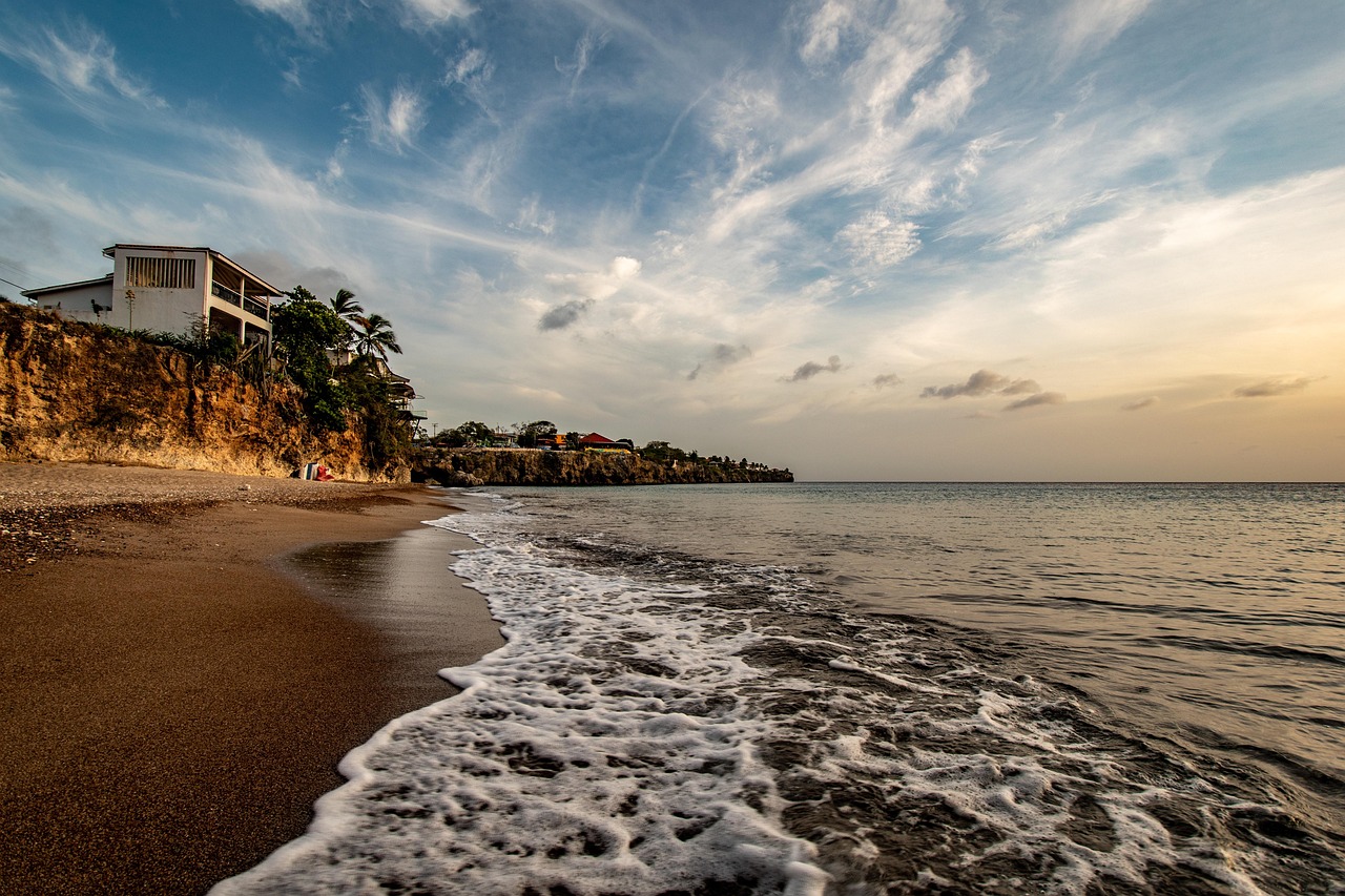 Couché de soleil sur une vaste plage avec une maison à gauche et la mer à droite.