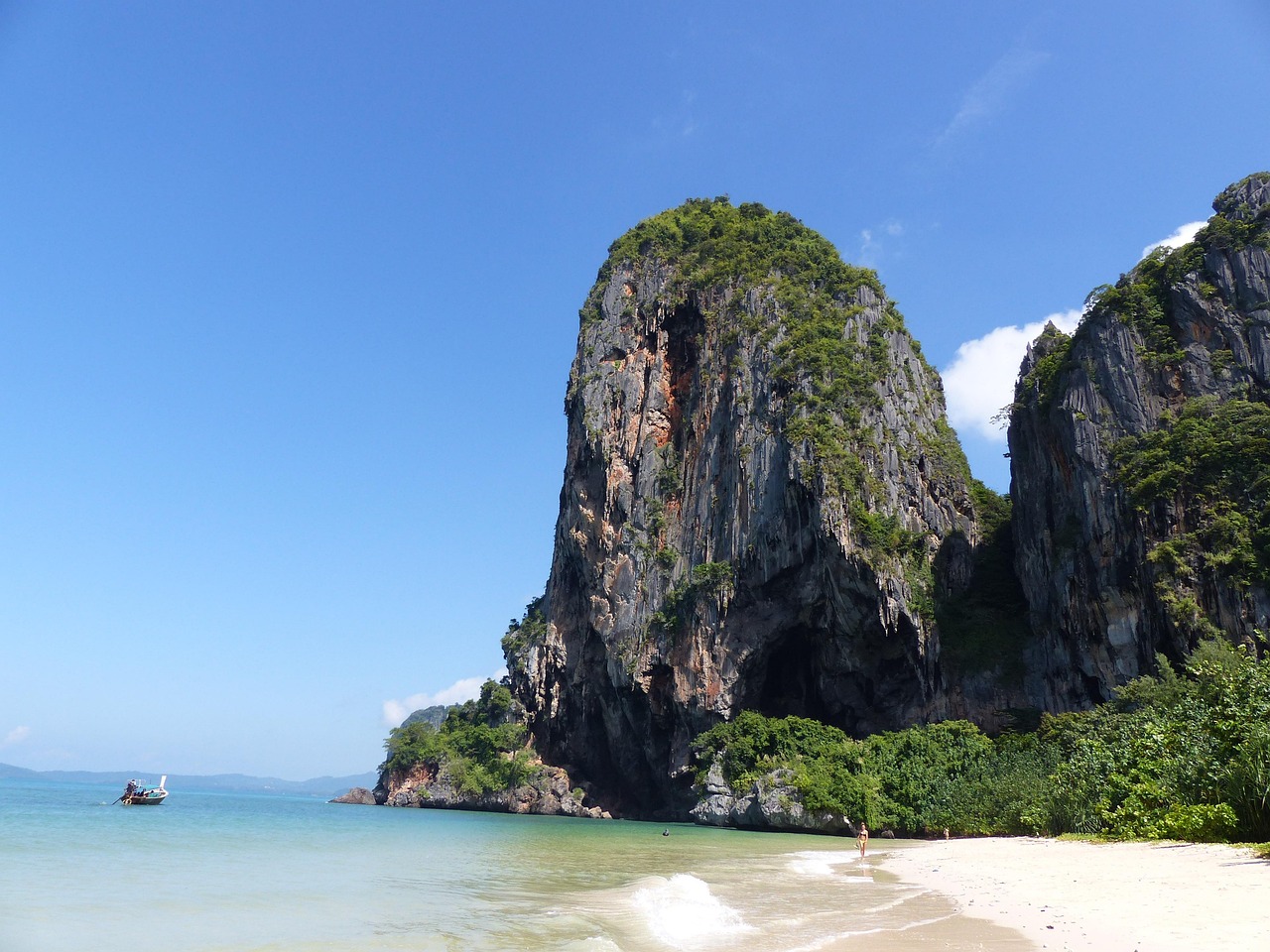 Vaste plage avec une mer bleue et des montagnes grises et vertes.